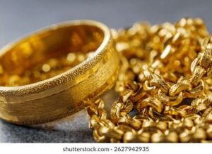 Närbild på en mönstrad guldring och en glittrande guldkedja.