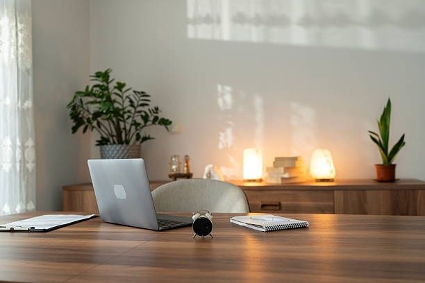 Laptop, anteckningsblock och klocka på ett träbord i ett ljust kontor